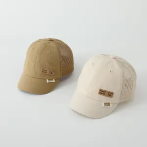 Detailed close-up of khaki and beige mesh summer baseball caps for kids with bear leather patch