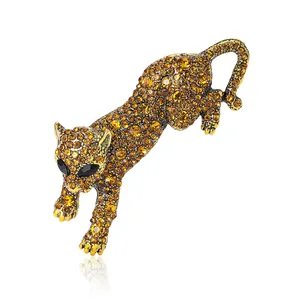 Spilla a leopardo dorata con strass ambra e occhi di gemme nere su sfondo bianco