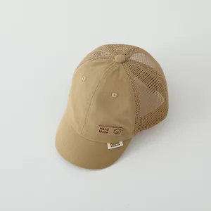 Detail view of khaki mesh trucker hat featuring a bear leather patch and short brim