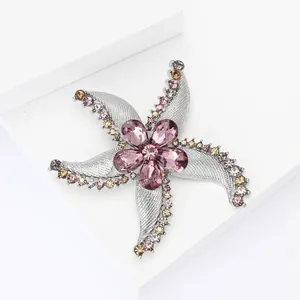 Exquisite starfish and flower brooch with pink rhinestones on a white geometric stand