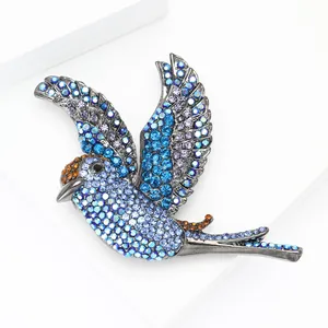 Vue macro d'une broche oiseau avec strass dégradés bleu et violet sur alliage foncé