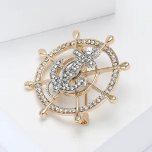 Macro detail of nautical anchor and helm brooch with sparkling rhinestones and gold plating