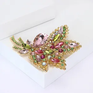 Detailed close-up of leaf brooch with pink pear-cut crystals and green rhinestones