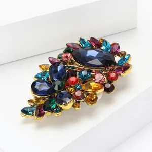 Nahaufnahme einer Vintage-Brosche aus Goldlegierung mit bunten Kristallen und Krallenfassung