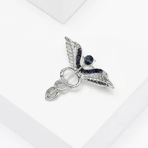 Détail de la broche médicale caducée en alliage argenté avec ailes en strass bleu foncé