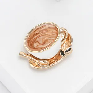 Macro detail of enamel coffee cup brooch with latte art pattern and small gold spoon