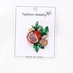 Macro detail of red pomegranate brooch with enamel leaves and sparkling crystals