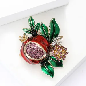 Exquisite pomegranate brooch with red enamel and pink rhinestones on a white stand