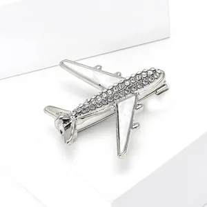 Detailed view of silver airplane brooch featuring sparkling rhinestones and white enamel