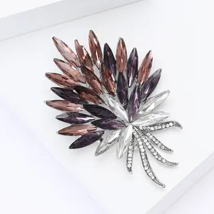 Détail macro d'une broche en cristal en forme de feuille avec strass multicolores