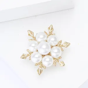 Gros plan d'une élégante broche flocon en or avec perles blanches sur fond blanc