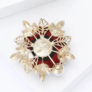 Detail of elegant rhinestone rose brooch featuring gold base, safety pin, and pearl accent