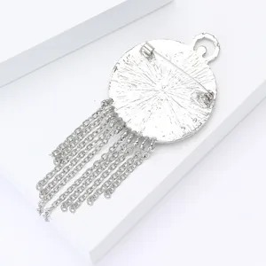 Detailweergave van de zilveren emaille broche met speldsluiting en metalen kwastjes