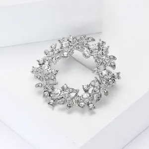 Détail macro d'une broche couronne florale argentée avec des cristaux étincelants