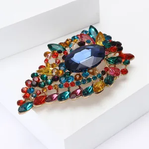 Vintage gold alloy brooch with colorful crystals and blue oval stone on white base