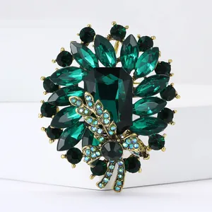 Vintage emerald crystal brooch with gold-plated leaf accents on a white background