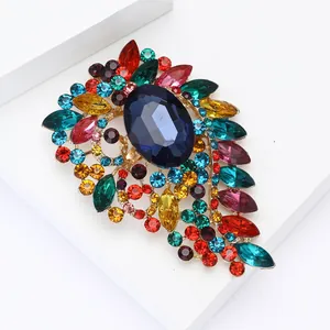 Macro detail of alloy brooch with colorful crystals and blue centerpiece on white base