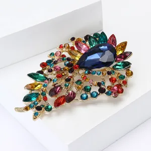 Broche élégante en alliage doré avec grands cristaux colorés et centre goutte bleue