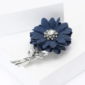 Close-up of navy blue fabric daisy brooch with silver alloy stems and rhinestone details