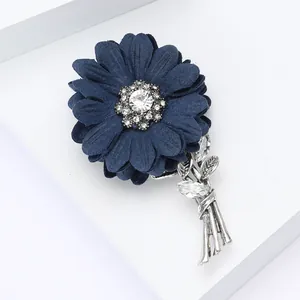 Elegant navy fabric flower brooch with rhinestones and silver metal on white display