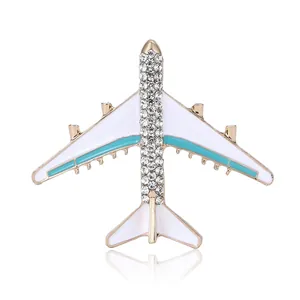 Fashionable golden airplane brooch with white enamel wings and sparkling crystal rhinestones