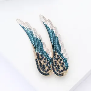 Détail de broches ailes d'ange en émail bleu avec cristaux et bordure dorée