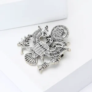 Vintage silver eagle brooch pin with detailed wing feathers on a white geometric block