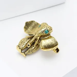 Vintage gold elephant brooch with emerald green gemstone eyes and textured metal finish
