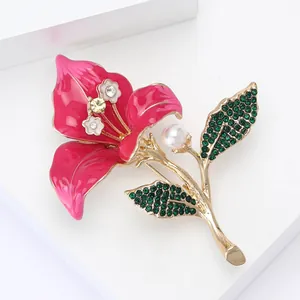 Vue macro de la broche fleur en émail avec strass et perle blanche sur un socle blanc