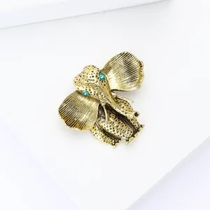 Detail showing the vintage gold elephant brooch with green rhinestone eyes and textured finish