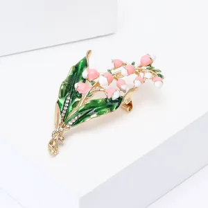 Detailed macro of lily of the valley brooch with enamel leaves and crystal accents