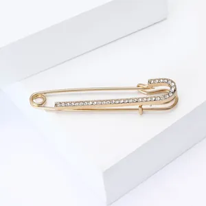 Makro-Detail der eleganten goldenen Sicherheitsnadel-Brosche mit funkelndem Strass-Besatz