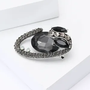 Macro shot of vintage alloy brooch featuring faceted black oval gem and grey rhinestones