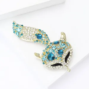 Close-up of golden fox brooch with blue rhinestones on minimalist white platform