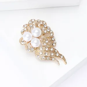 Detail showing elegant gold alloy flower brooch with three pearls and crystal tassels