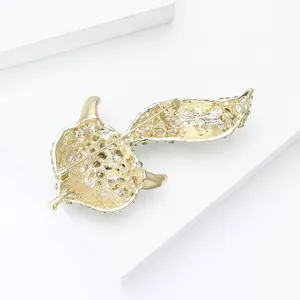Macro shot of gold-plated bird brooch back with intricate relief texture and pin clasp