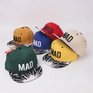 Détail de casquettes snapback enfant brodées MAD avec visières plates à taches de peinture