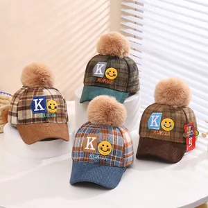 Detail of children's plaid baseball cap with plush pom-pom and K embroidery