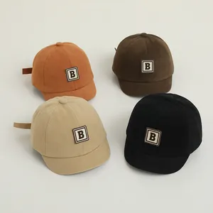 Flat lay of soft cotton baby baseball caps in earth tones with white letter B patch