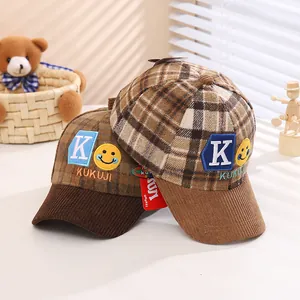 Close-up of children's plaid baseball caps with K embroidery and velvet brim details