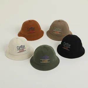 Detail showing five corduroy fisherman hats in caramel, beige, and green with letter embroidery