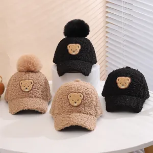 Detail of plush beige and black winter baseball caps with cute bear embroidery and pom-poms