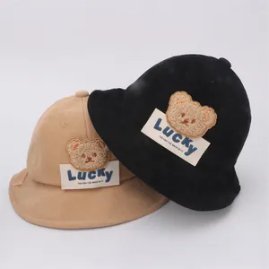 Dettaglio dei cappelli a secchiello in velluto nero e beige con toppa a orsetto