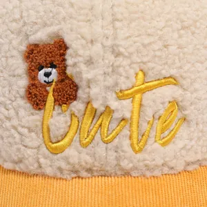 Detail of plush lamb wool hat with orange corduroy brim and cute bear embroidery