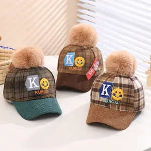 Detailed view of kids checkered baseball hats with plush pom-poms and corduroy brims