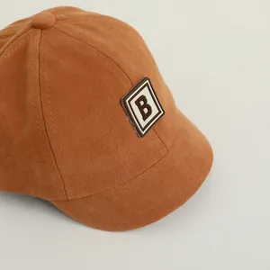 Detail view of mustard yellow cotton baseball cap featuring an embroidered B-letter patch