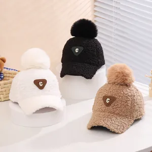 Detailansicht der flauschigen Winter-Baseballkappen in Weiß, Schwarz und Khaki mit Fellbommeln