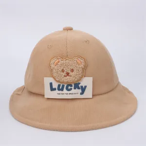 Dettaglio cappello pescatore in velluto a coste marrone chiaro con orsetto e scritta Lucky
