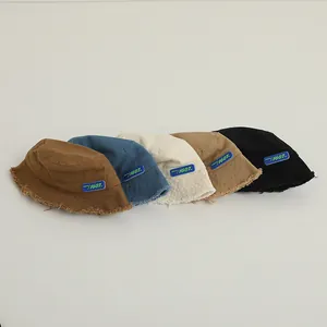 Détail de cinq chapeaux bobs en velours côtelé avec bords effilochés en marron, bleu et beige