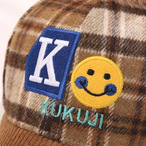 Detail of checkered plush kids baseball cap with fluffy pompom and K letter embroidery